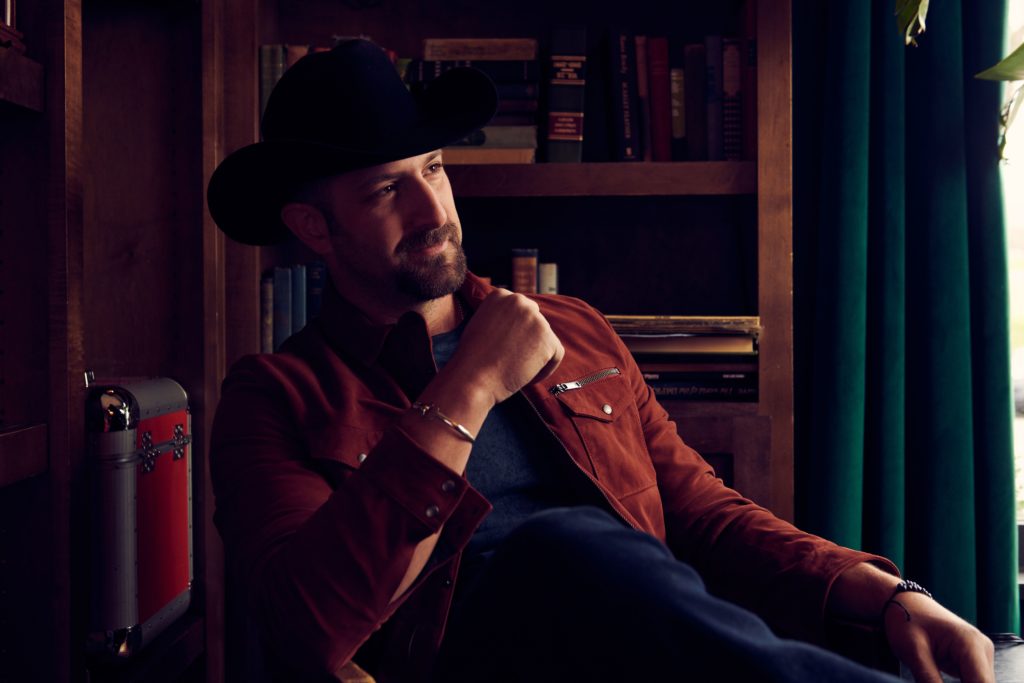 Buckstein sits while wearing cowboy hat and brown leather jacket