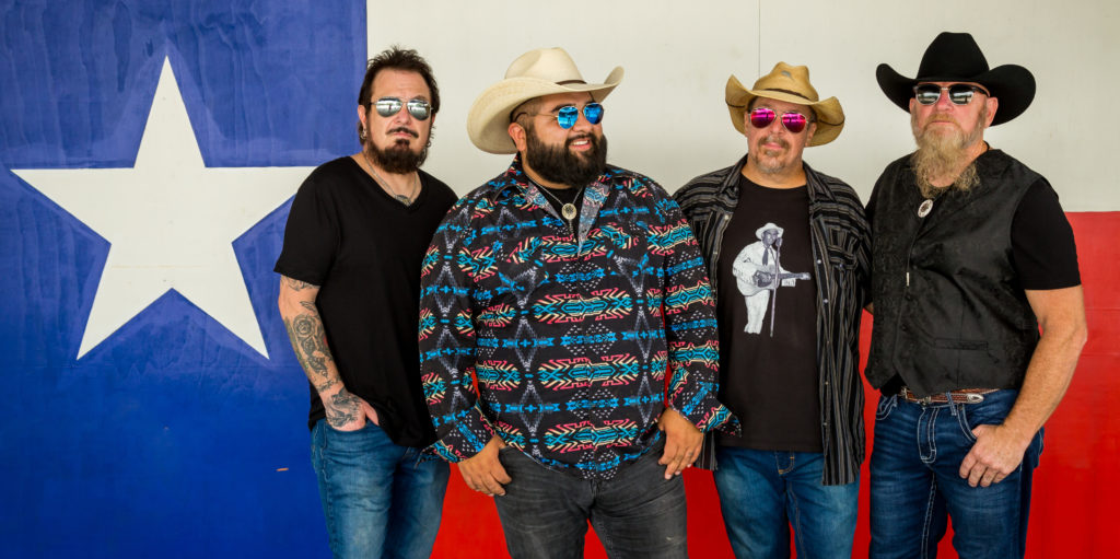 Kin Faux standing in front of Texas state flag. From left to right, Jakey Black, Rico Gonzales, Ross Barkey, Dan Currier.